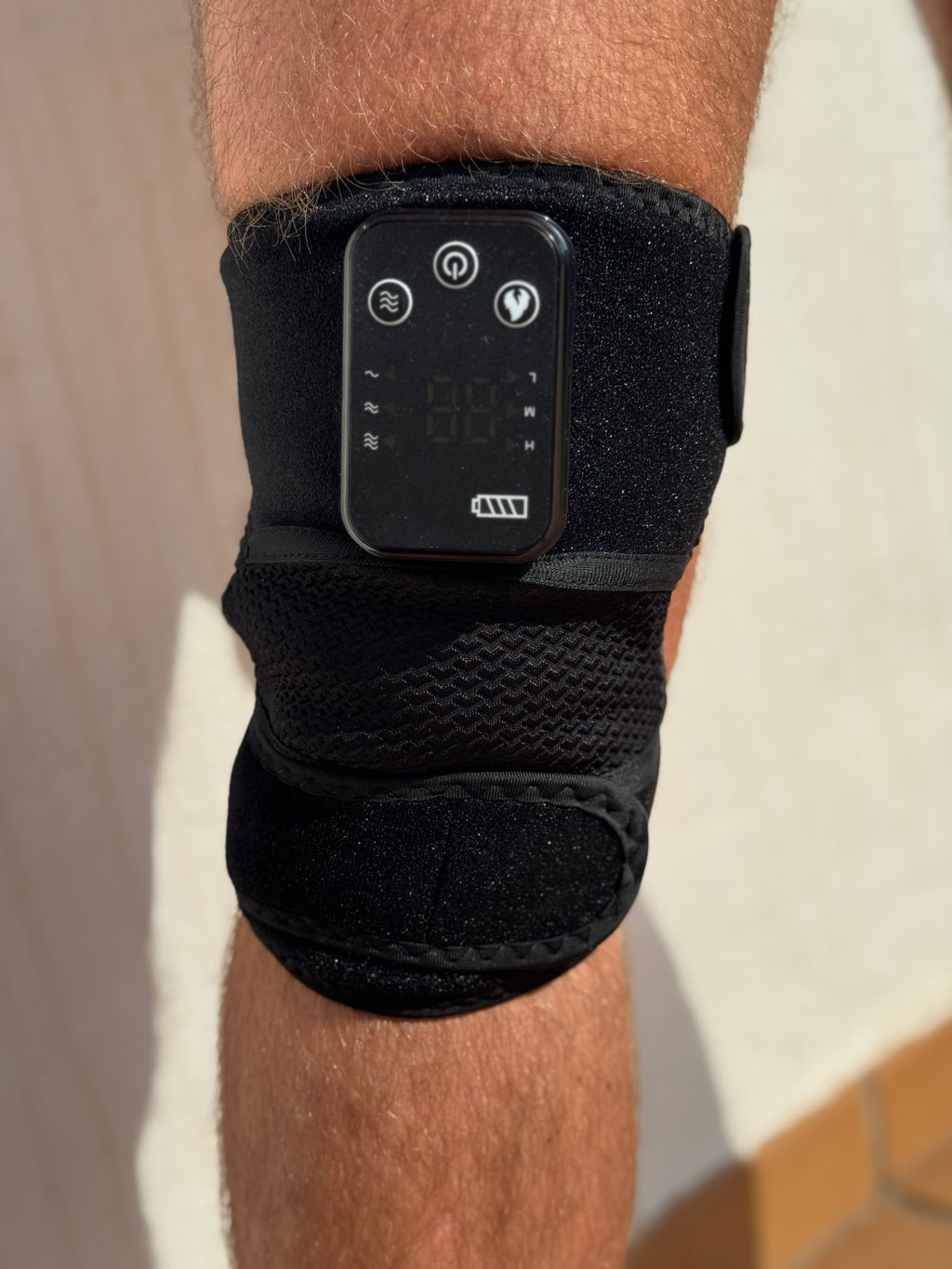 RecoverWave Knee Wrap Pro worn on knee, real product photo, control panel and display on